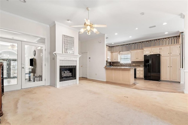 interior space featuring ornamental molding, french doors, a tile fireplace, and light carpet