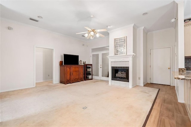 living room featuring a tile fireplace, ceiling fan, and ornamental molding