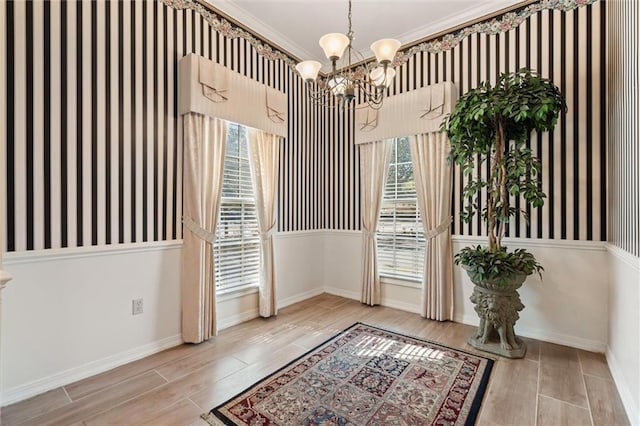 doorway featuring a chandelier, baseboards, wood finish floors, and ornamental molding