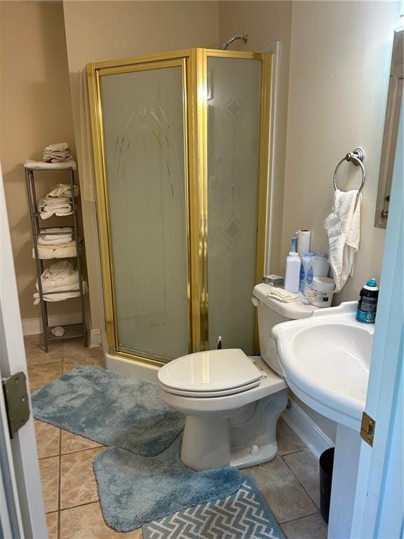 bathroom with a shower with shower door, toilet, and tile patterned floors