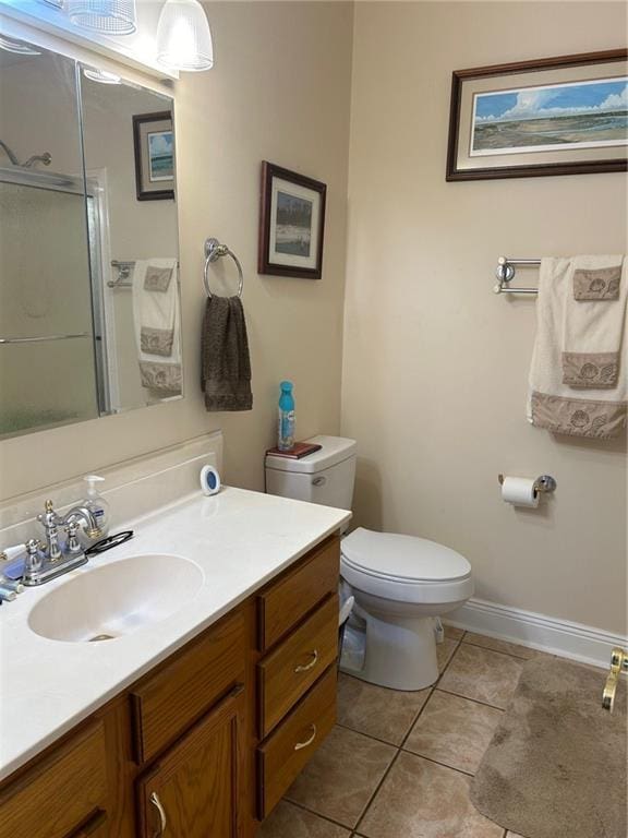 full bathroom featuring baseboards, toilet, vanity, tile patterned flooring, and a shower with door