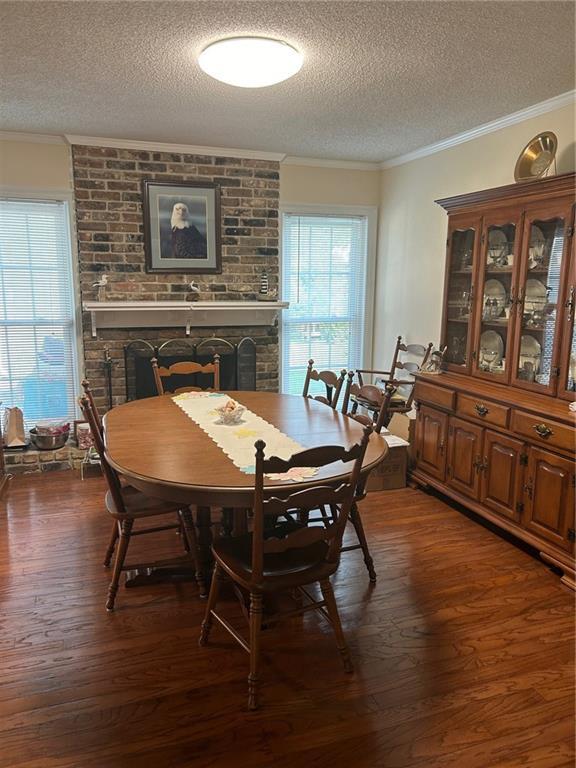 dining space with dark wood-type flooring, crown molding, and a brick fireplace