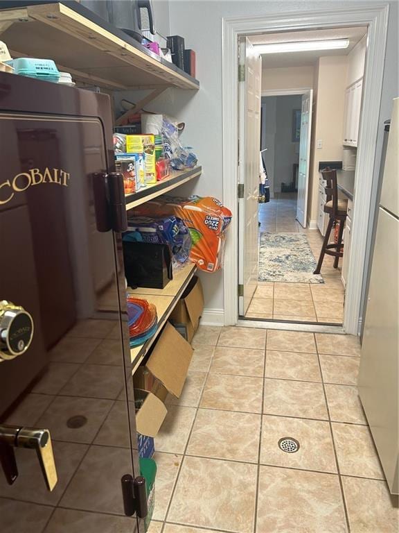 clothes washing area with light tile patterned floors and baseboards