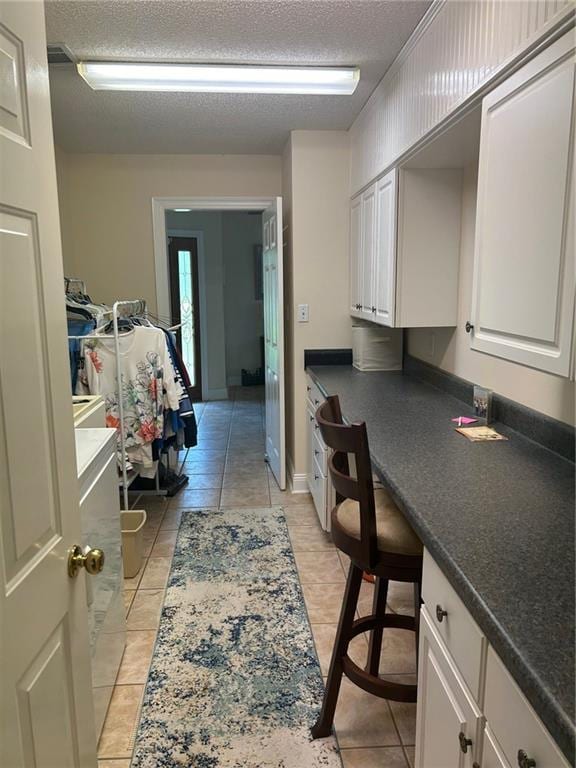 interior space featuring white cabinets, light tile patterned flooring, and a textured ceiling