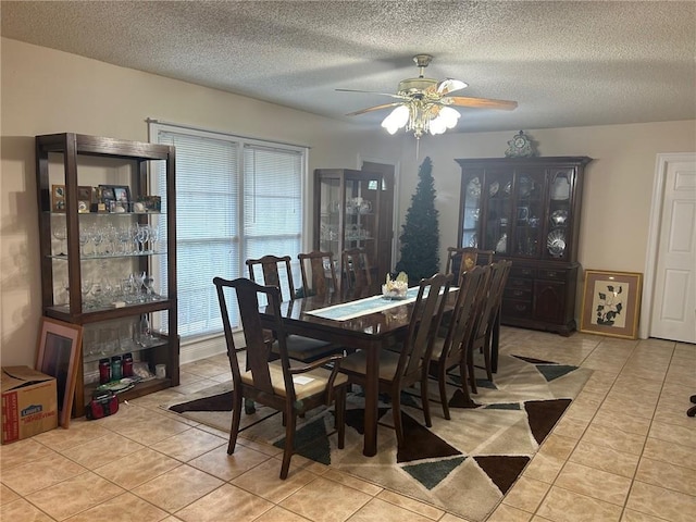 tiled dining space with a textured ceiling and ceiling fan