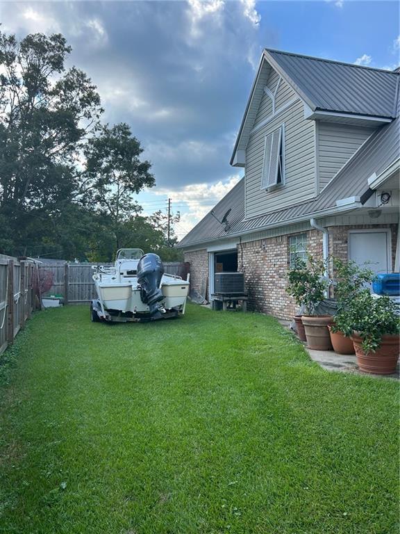 exterior space featuring a yard, fence, and brick siding