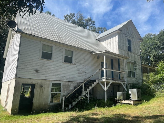 rear view of property featuring cooling unit and a yard