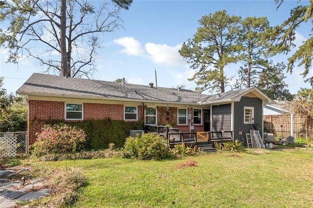 back of house featuring brick siding, a deck, a lawn, and fence