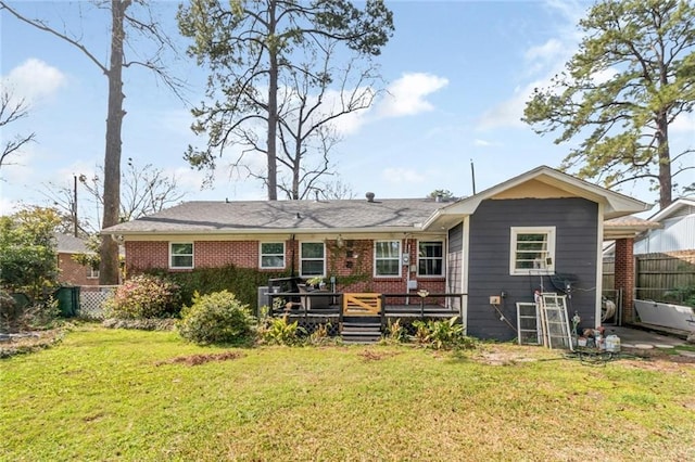 rear view of house featuring a deck, a yard, fence, and brick siding