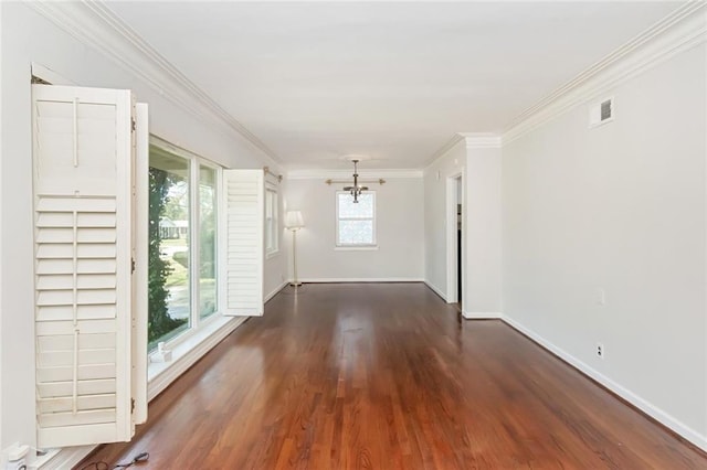 empty room featuring visible vents, wood finished floors, an inviting chandelier, crown molding, and baseboards