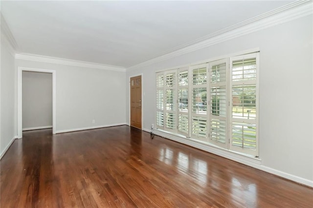 spare room featuring ornamental molding, baseboards, and wood finished floors