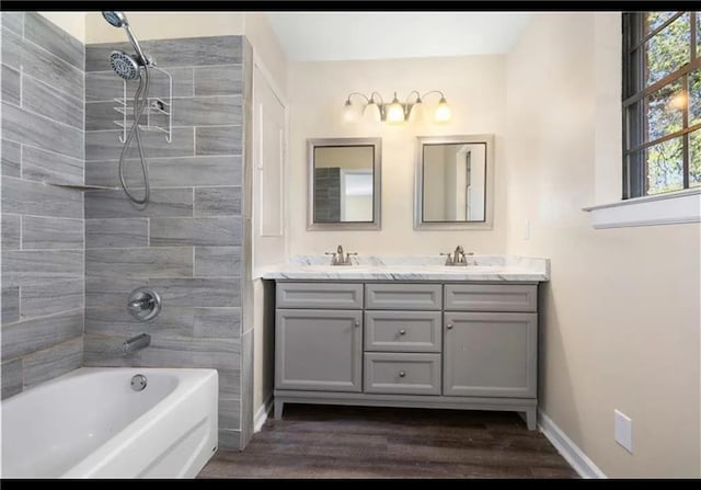 full bathroom with double vanity, baseboards, wood finished floors, bathtub / shower combination, and a sink