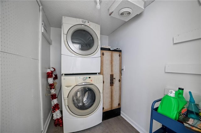 clothes washing area with stacked washing maching and dryer, dark hardwood / wood-style floors, and a textured ceiling