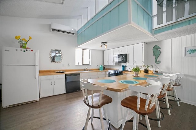 kitchen featuring butcher block counters, a wall mounted AC, dark hardwood / wood-style flooring, white cabinets, and black appliances