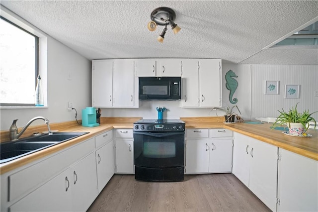 kitchen featuring sink, light hardwood / wood-style floors, white cabinets, and black appliances