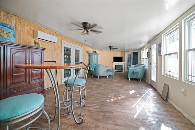 sunroom featuring ceiling fan, an AC wall unit, and plenty of natural light