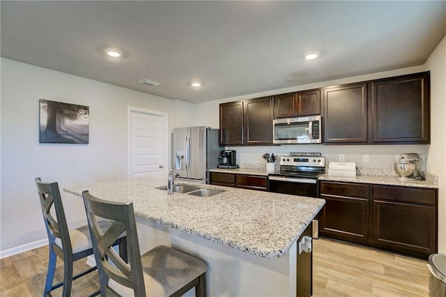 kitchen with a kitchen breakfast bar, sink, stainless steel appliances, and light hardwood / wood-style floors