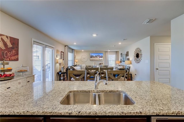 kitchen featuring french doors, sink, and light stone counters