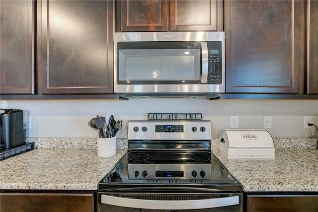 kitchen with dark brown cabinetry, stainless steel appliances, and light stone counters