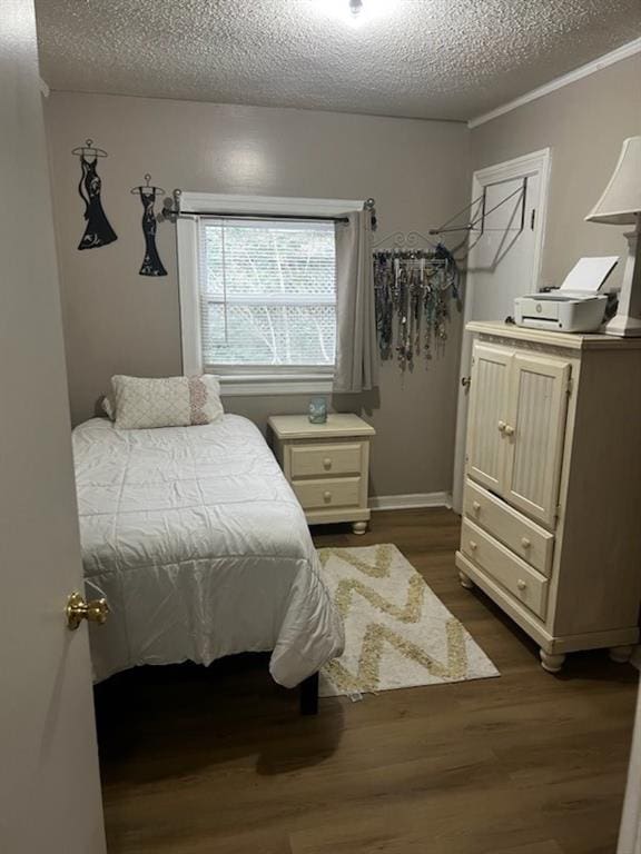 bedroom with dark wood-type flooring, a textured ceiling, and crown molding