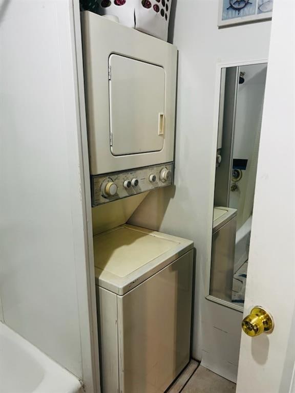 laundry room with light tile patterned flooring and stacked washer and clothes dryer