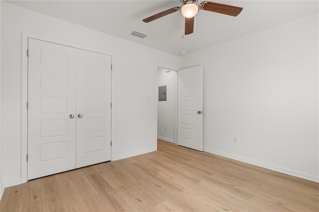 unfurnished bedroom featuring light wood-type flooring, a closet, electric panel, visible vents, and baseboards