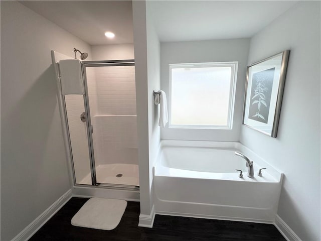 full bath featuring a stall shower, baseboards, a garden tub, and wood finished floors