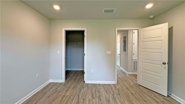 unfurnished bedroom featuring light wood-type flooring, a spacious closet, and a closet