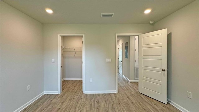 unfurnished bedroom featuring a walk in closet, a closet, and light wood-type flooring