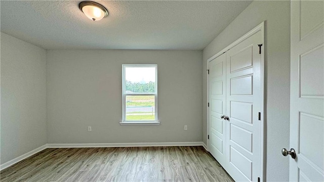 unfurnished bedroom featuring a textured ceiling, light hardwood / wood-style flooring, and a closet