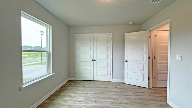 unfurnished bedroom with light hardwood / wood-style floors and a closet