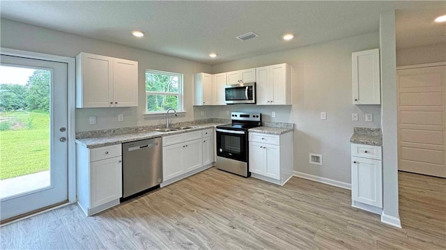 kitchen featuring appliances with stainless steel finishes, light wood-type flooring, a sink, and white cabinetry