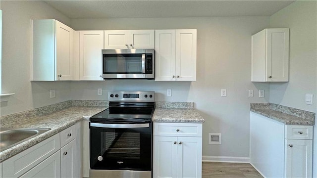 kitchen with white cabinetry, light stone countertops, and appliances with stainless steel finishes