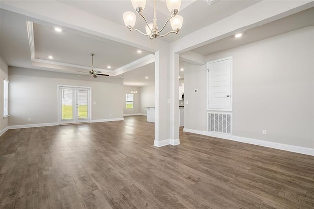 interior space featuring ceiling fan with notable chandelier, a raised ceiling, and dark hardwood / wood-style flooring