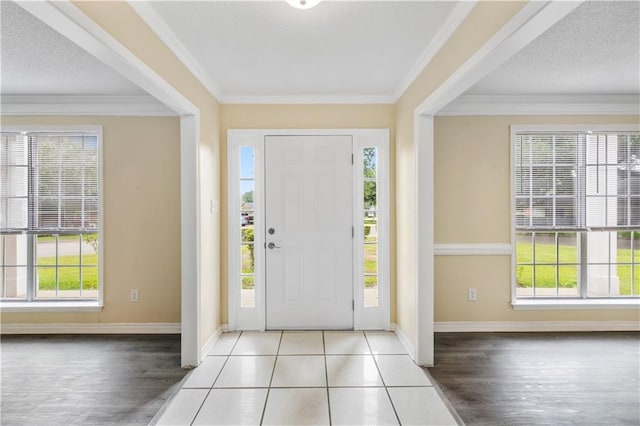 entryway featuring a wealth of natural light, tile patterned flooring, and ornamental molding