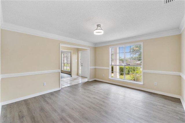 unfurnished room with light hardwood / wood-style floors, a textured ceiling, a healthy amount of sunlight, and crown molding