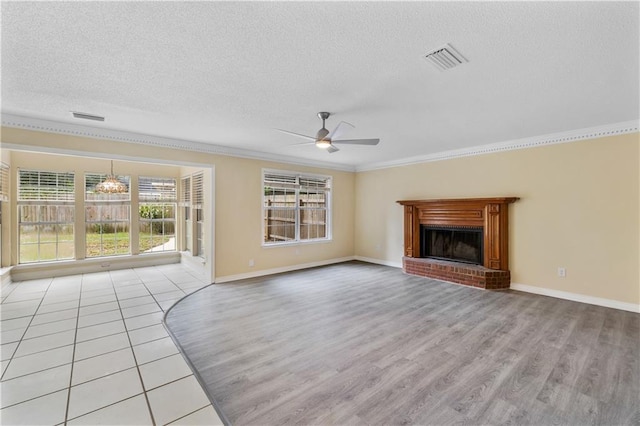 unfurnished living room with light hardwood / wood-style floors, ceiling fan with notable chandelier, a textured ceiling, a fireplace, and crown molding