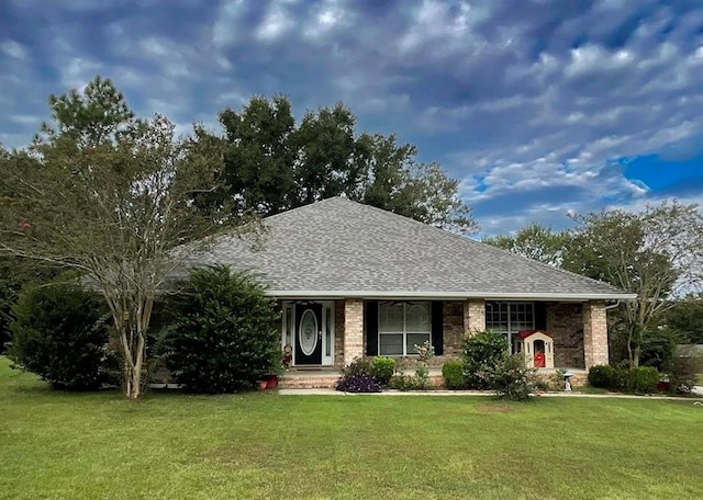 ranch-style house featuring roof with shingles, brick siding, and a front lawn