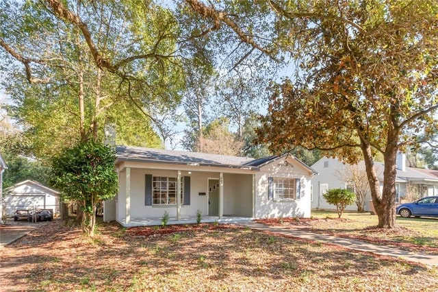 view of front of home featuring covered porch, an outbuilding, and stucco siding