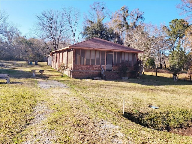 view of side of home featuring a sunroom and a yard