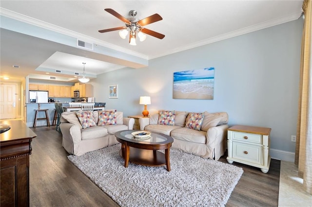 living room featuring visible vents, baseboards, ornamental molding, dark wood-style floors, and a tray ceiling