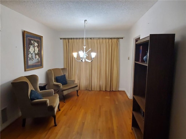 sitting room with a textured ceiling, an inviting chandelier, and hardwood / wood-style flooring