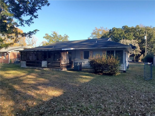 rear view of property featuring cooling unit, a sunroom, and a lawn