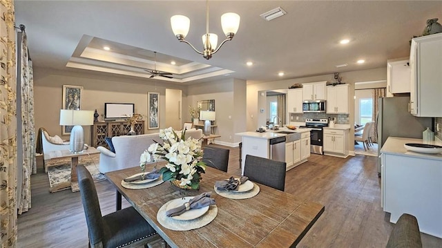 9851 Nadine Ln, Mobile, AL 36695 - dining area featuring dark wood-style flooring, a chandelier, a ceiling fan, recessed lighting, and a tray ceiling