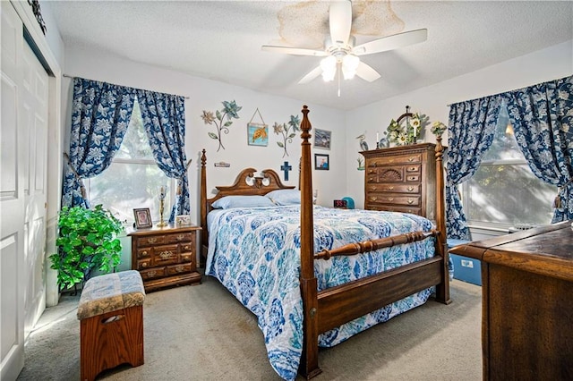 bedroom featuring a closet, ceiling fan, a textured ceiling, and light colored carpet