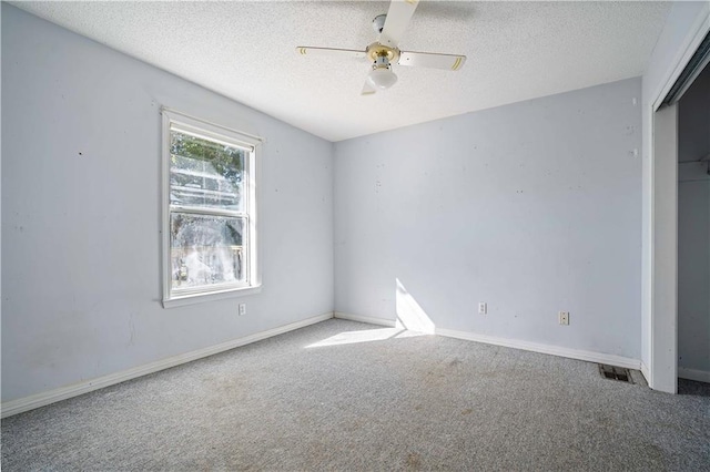 unfurnished bedroom featuring carpet, a textured ceiling, a closet, and ceiling fan