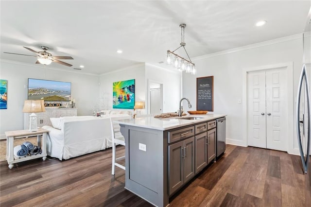 kitchen featuring sink, a kitchen island with sink, dark hardwood / wood-style floors, ornamental molding, and decorative light fixtures