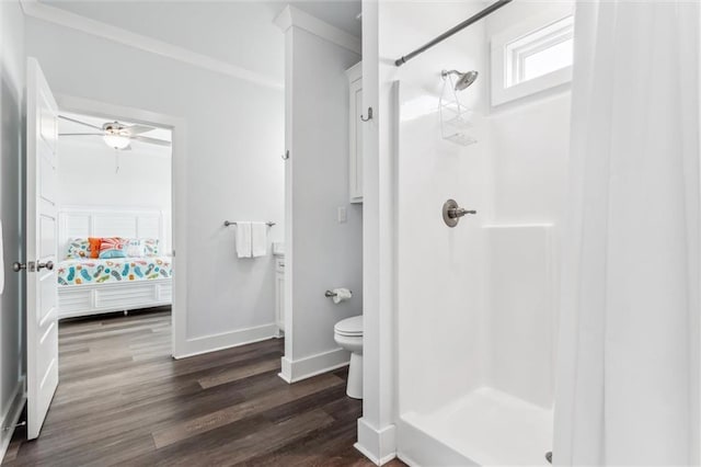 bathroom with hardwood / wood-style flooring, toilet, crown molding, and walk in shower