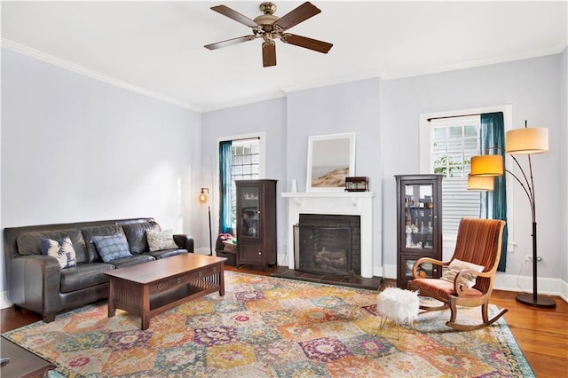 living room with crown molding, a fireplace, a wealth of natural light, and wood finished floors