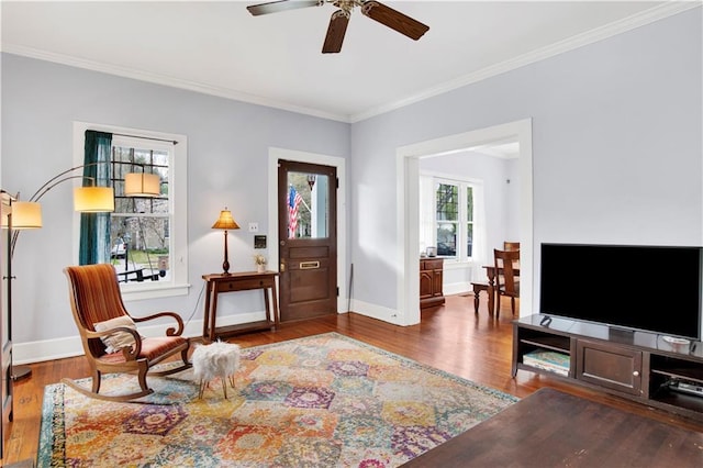 sitting room with a ceiling fan, baseboards, ornamental molding, and wood finished floors